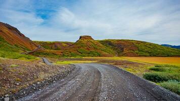 panoramisch over- IJslands kleurrijk en wild vulkanisch landschap en grind uit weg bijhouden Bij zomer en blauw lucht, IJsland foto