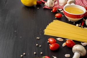 spaghetti-ingrediënten op zwart houten bureau, bovenaanzicht.