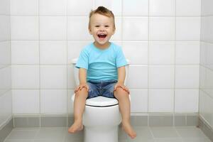 opgewonden kind zittend Aan toilet. normaal darm gewoonte concept. foto