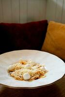 heerlijk spaghetti met mozarella ballen en tomaat saus Aan houten tafel in cafe foto