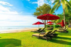 rode parasols en strandstoelen met zee strand achtergrond en blauwe lucht en zonlicht foto