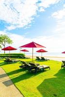 rode parasols en strandstoelen met zee strand achtergrond en blauwe lucht en zonlicht