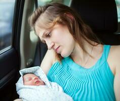 vrouw Holding pasgeboren baby zittend in de auto foto