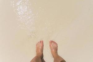op blote voeten in de golven op het strand staan foto