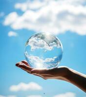 dichtbij omhoog van menselijk hand- Holding glas wereldbol met blauw lucht achtergrond. foto