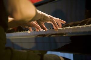 detailopname Aan de handen van een vrouw spelen de piano met muziek- sleutels foto