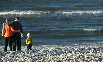 familie van drie Aan kiezelsteen strand foto