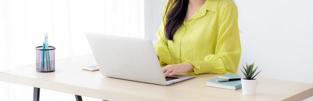 jonge Aziatische zakenvrouw werkt op laptopcomputer op bureau thuiskantoor, freelance kijken en typen op notebook op tafel, levensstijl van vrouw die online studeert, bedrijfs- en onderwijsconcept. foto