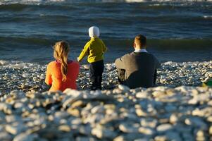 familie van drie Aan kiezelsteen strand foto