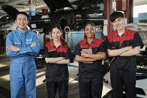 portret van multiraciaal professioneel monteur team armen gekruiste en kijken Bij camera, werk Bij auto onderhoud garage, gelukkig onderhoud banen, controleren en reparatie bezetting in automotive industrie bedrijf. foto