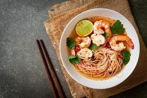 noedels met pittige soep en garnalen in witte kom, of tom yum kung - Aziatisch eten foto