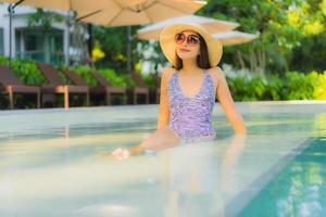 mooie jonge aziatische vrouwen gelukkige glimlach ontspannen rond het buitenzwembad in het hotelresort voor reizen in vakantievakantie foto