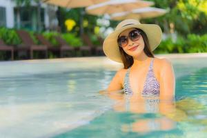 mooie jonge aziatische vrouwen gelukkige glimlach ontspannen rond het buitenzwembad in het hotelresort voor reizen in vakantievakantie foto