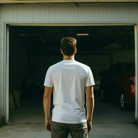 ai generatief een Mens vervelend een duidelijk wit t - overhemd Aan de garage geconfronteerd achteruit, perfect naar creëren t-shirt mockup foto