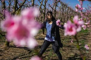 vrouw wandelen door velden van bloeiend perzik bomen in de lente. foto