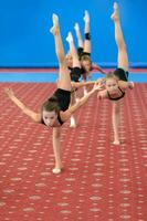 jong vrouw gymnasten aan het doen verticaal been-split foto