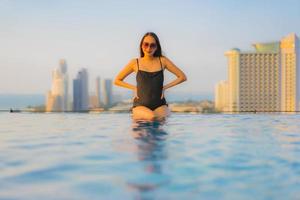 portret mooie jonge aziatische vrouwen gelukkig glimlach ontspannen buitenzwembad in hotel foto