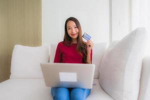 portret mooie jonge aziatische vrouwen die computerlaptop met mobiele telefoon en creditcard gebruiken foto