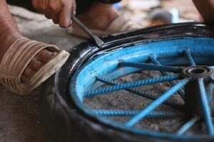 een Indonesisch onderhoud arbeider is veranderen de band van een fiets kar handmatig foto