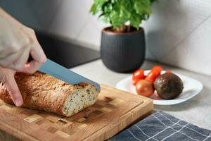 vrouw snijdend brood van brood met groot mes foto