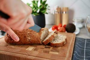 vrouw snijdend brood van brood met groot mes foto