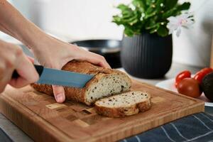 vrouw snijdend brood van brood met groot mes foto