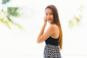 portret mooie jonge aziatische vrouw blij en glimlach met reizen in hotelresort in de buurt van zee en strand foto