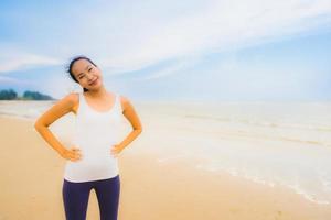 portret mooie jonge sport aziatische vrouw oefenen door te rennen en joggen op het natuurstrand en de zee in de buitenlucht foto