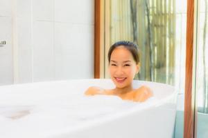 portret jonge mooie aziatische vrouw neemt een bad in badkuip foto