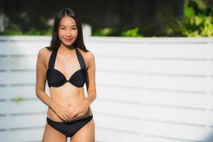 portret mooie jonge aziatische vrouw gelukkige glimlach ontspannen rond het buitenzwembad outdoor foto