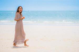 portret mooie jonge aziatische vrouw gelukkige glimlach ontspannen op het tropische strand zee oceaan foto