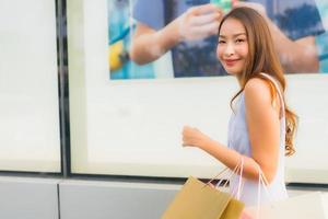 portret mooie jonge aziatische vrouw blij en glimlach met boodschappentas van warenhuis foto