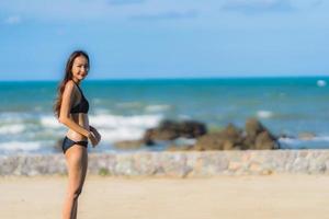 portret mooie jonge aziatische vrouw draagt bikini rond zwembad in hotelresort bijna zee oceaan strand foto