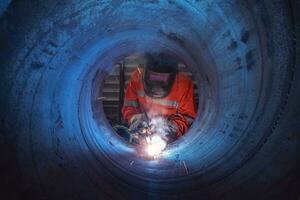 een arbeider met beschermend masker lassen staal structuur in een fabriek foto