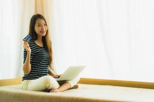 portret mooie jonge aziatische vrouw die computernotitieboekje of laptop met creditcard gebruikt om te winkelen foto