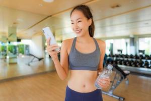 portret mooie aziatische jonge vrouw die mobiele telefoon in gymnastiek gebruikt foto