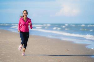 portret mooie jonge aziatische vrouw die loopt en oefent op het tropische natuurstrand, zee, oceaan foto