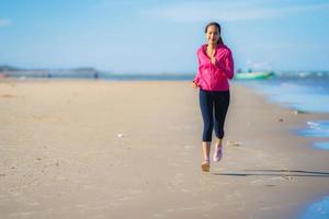 portret mooie jonge aziatische vrouw die loopt en oefent op het tropische natuurstrand, zee, oceaan foto