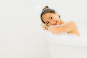 portret mooie jonge aziatische vrouw neemt een badkuip in de badkamer foto