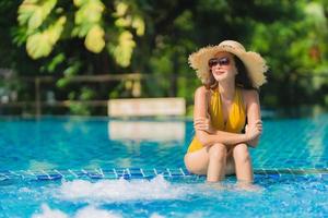 portret mooie jonge aziatische vrouw vrije tijd ontspannen glimlach en gelukkig rond het zwembad in hotelresort foto