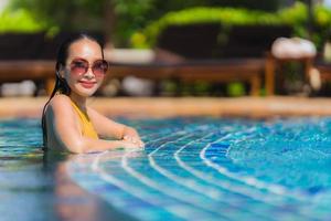 portret mooie jonge aziatische vrouw vrije tijd ontspannen glimlach en gelukkig rond het zwembad in hotelresort foto