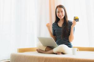 portret mooie jonge aziatische vrouw die computernotitieboekje of laptop met creditcard gebruikt om te winkelen foto