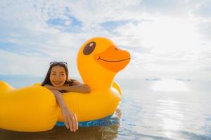portret jonge aziatische vrouw op opblaasbare vlotter gele eend rond buitenzwembad in hotel en resort foto
