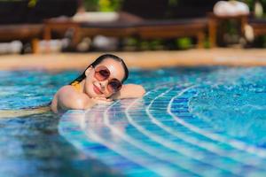 portret mooie jonge aziatische vrouw vrije tijd ontspannen glimlach en gelukkig rond het zwembad in hotelresort foto