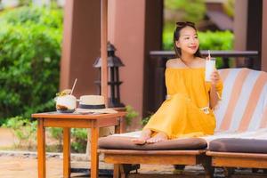 portret mooie jonge aziatische vrouw vrije tijd ontspannen glimlach en blij met kokossap rond het zwembad in hotelresort foto