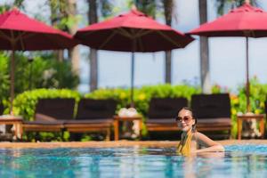 portret mooie jonge aziatische vrouw vrije tijd ontspannen glimlach en gelukkig rond het zwembad in hotelresort foto