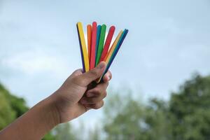 ijsje stokjes in regenboog kleuren Holding in handen van Aziatisch jongen, zacht en selectief focus, concept voor roeping uit allemaal mensen naar ondersteuning lgbt evenementen en campagnes in de omgeving van de wereld. foto