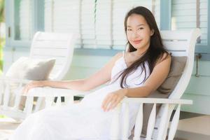 portret mooie jonge aziatische vrouw zit op een houten stoel rond het buitenterras foto