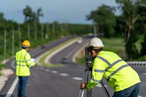 samenspel van landmeter ingenieurs arbeider maken meten met theodoliet instrument uitrusting gedurende bouw weg werken, civiel ingenieurs, landmeter apparatuur. foto