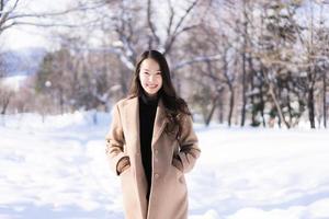 portret jonge mooie aziatische vrouw glimlach gelukkig reizen en genieten met sneeuw winterseizoen foto